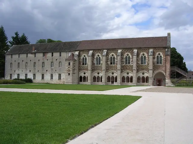 Cîteaux Abbey's 15th-century library building with its arched windows, across the lawn