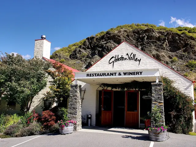 The Gibbston Valley Restaurant & Winery entrance, its sign on the white gable below the hillside (CC0)