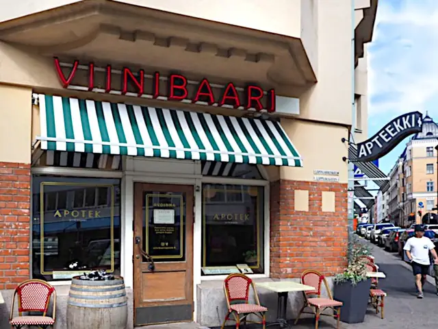Viinibaari Apotek’s corner: the red VIINIBAARI neon and striped awning beside the old APTEEKKI sign, terrace chairs out front