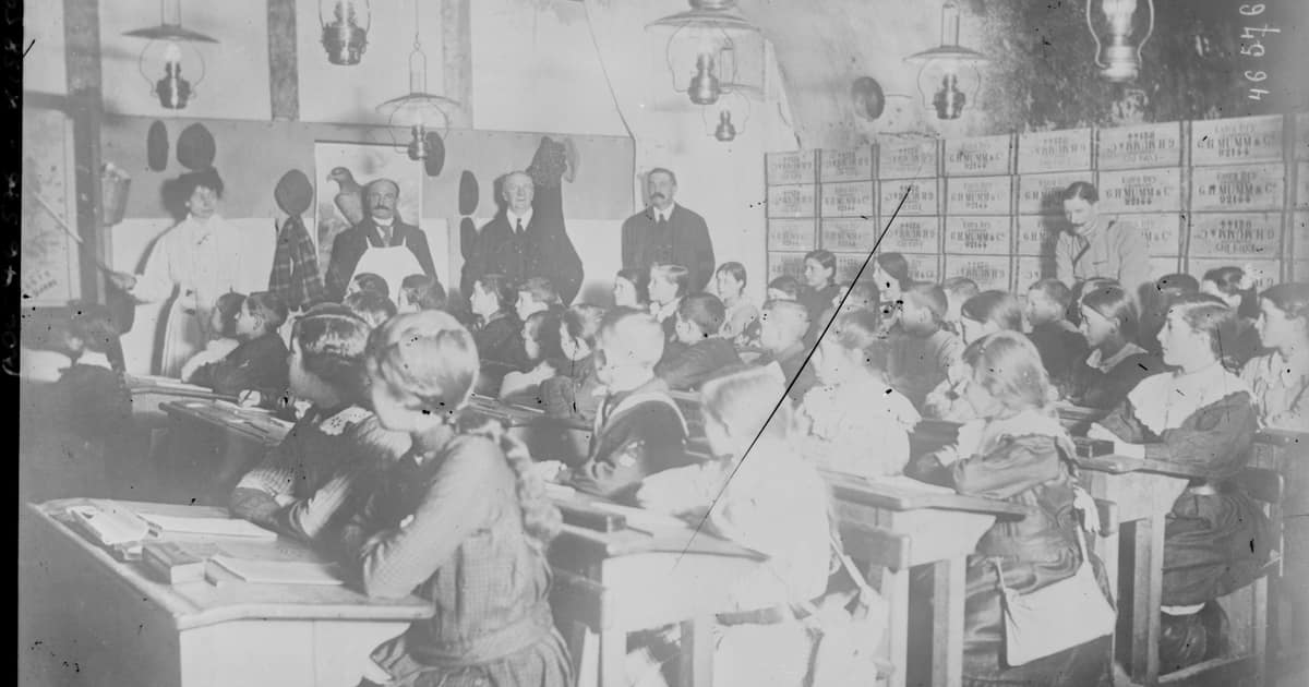 Black-and-white photo of children at school desks in a vaulted champagne cellar in Reims