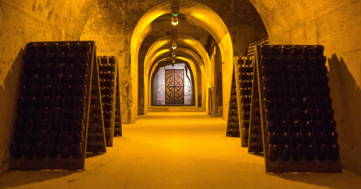A lit chalk gallery in the Taittinger cellars in Reims, riddling racks full of bottles on both sides