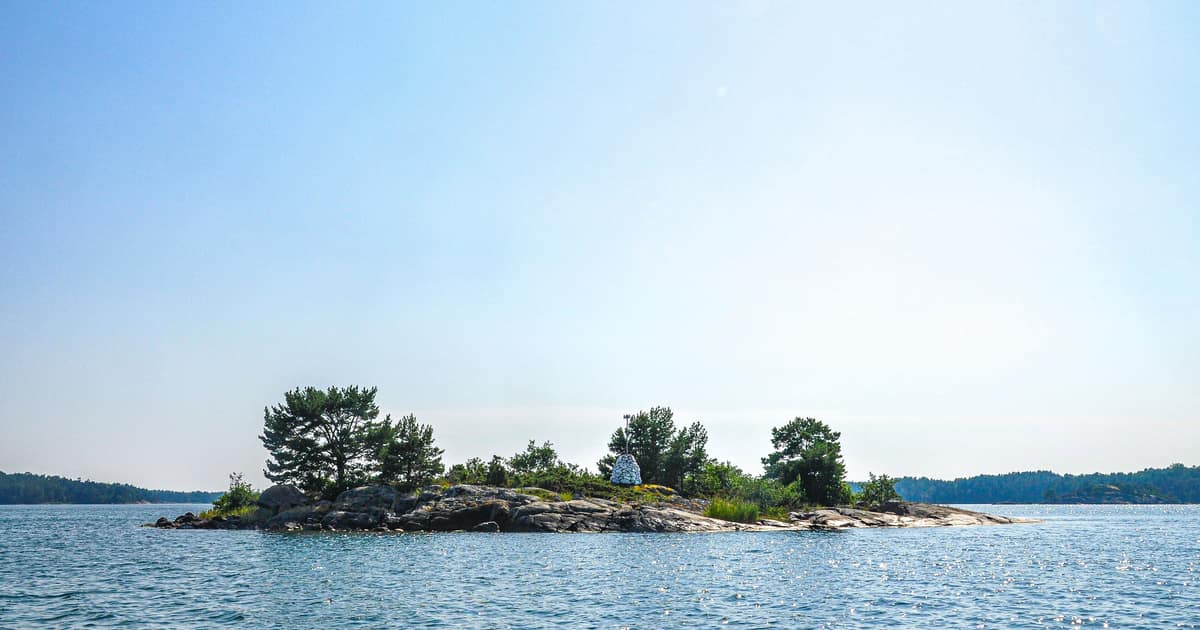 A small rocky islet with pine trees in calm blue water off Föglö, Åland
