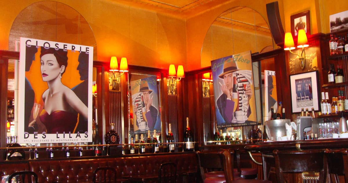 The bar at La Closerie des Lilas in Paris, with posters, red stools and bottles lit in warm light