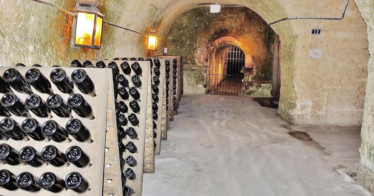 Champagne bottles neck-down in riddling racks along a chalk tunnel in the Mercier cellars, Épernay