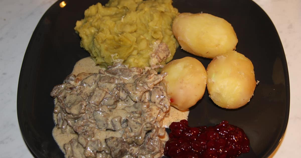 A plate of sautéed reindeer with boiled potatoes, mash and lingonberries