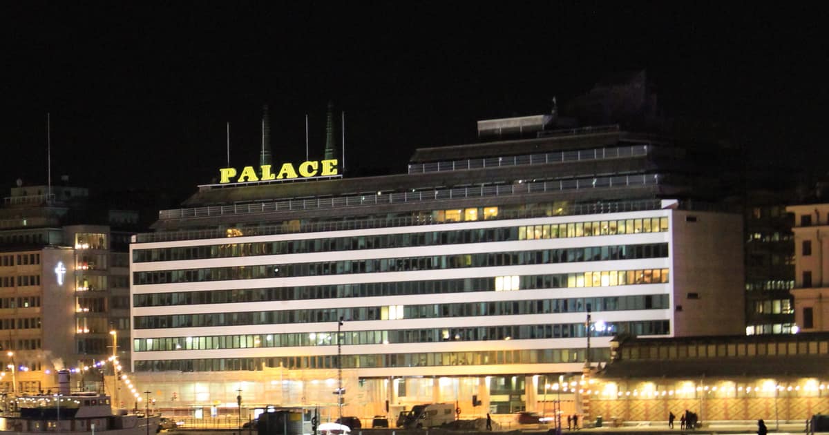 The Palace building on the Helsinki waterfront at night, its PALACE sign lit on the roof