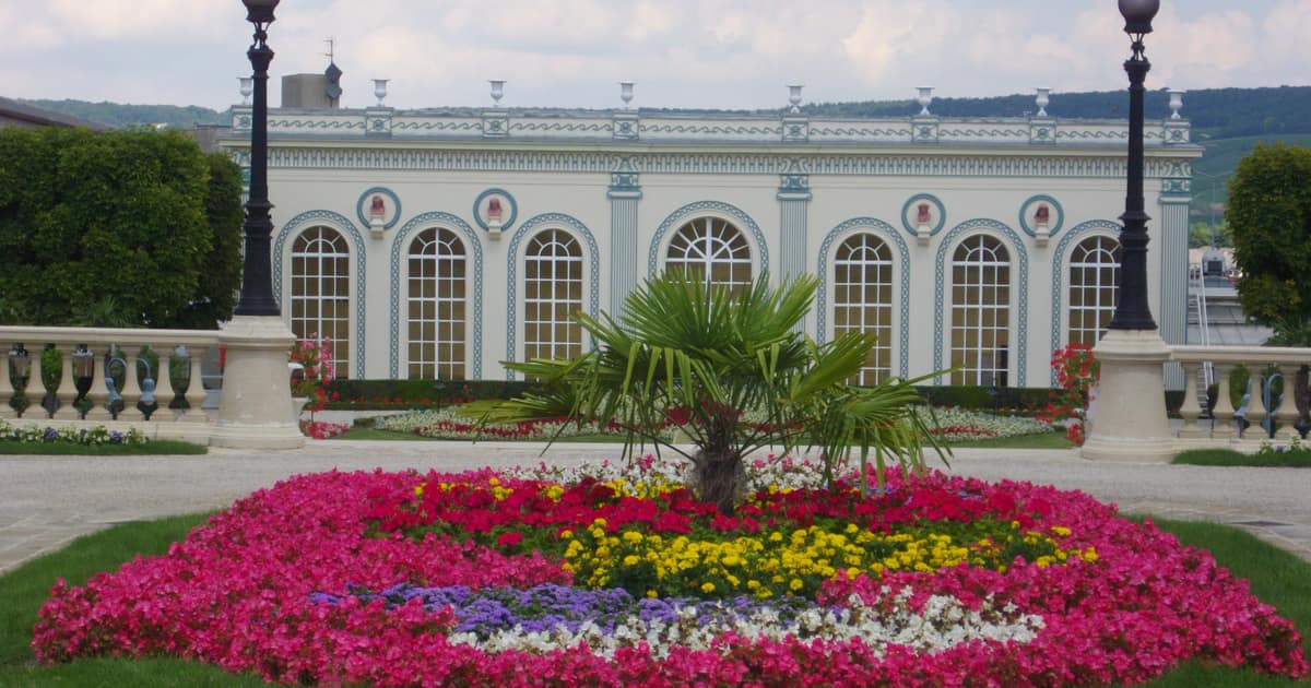 The white orangery of the Trianon on the avenue de Champagne in Épernay, a flower bed in front