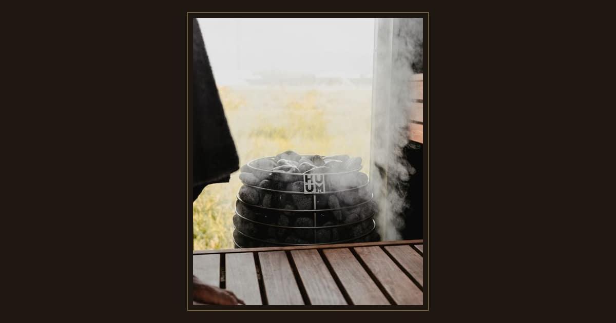 Steam rising from the stones of a sauna stove beside a wooden bench